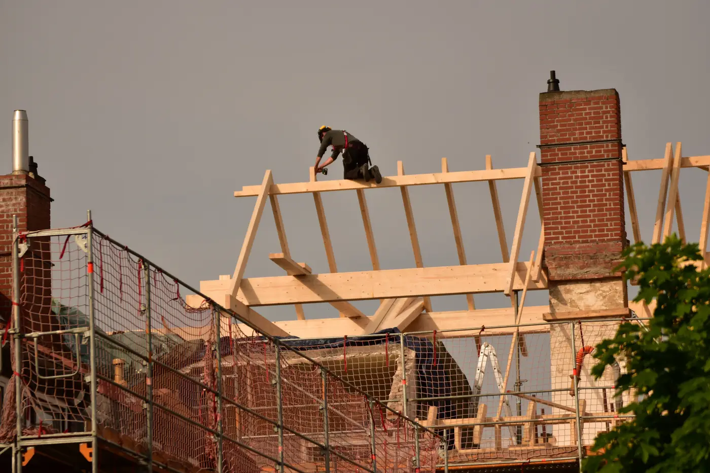 Un charpentier sur la charpente d'une maison en briques